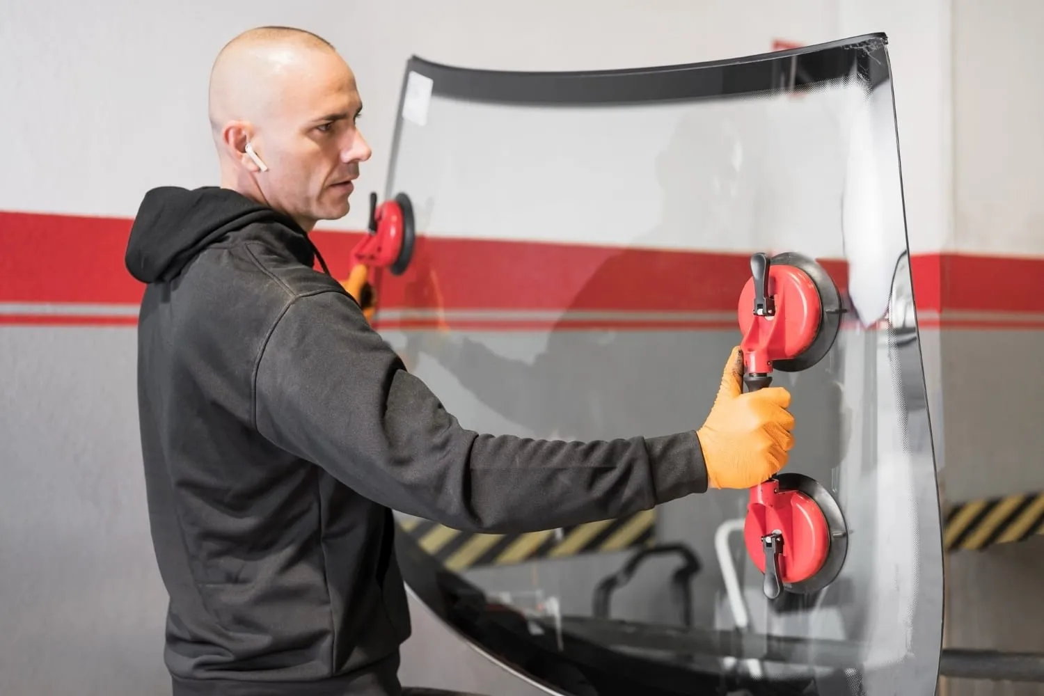 Technician holding a windshield with suction cups