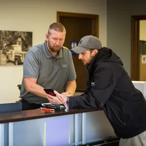 Two men talking over a tablet at the service counter
