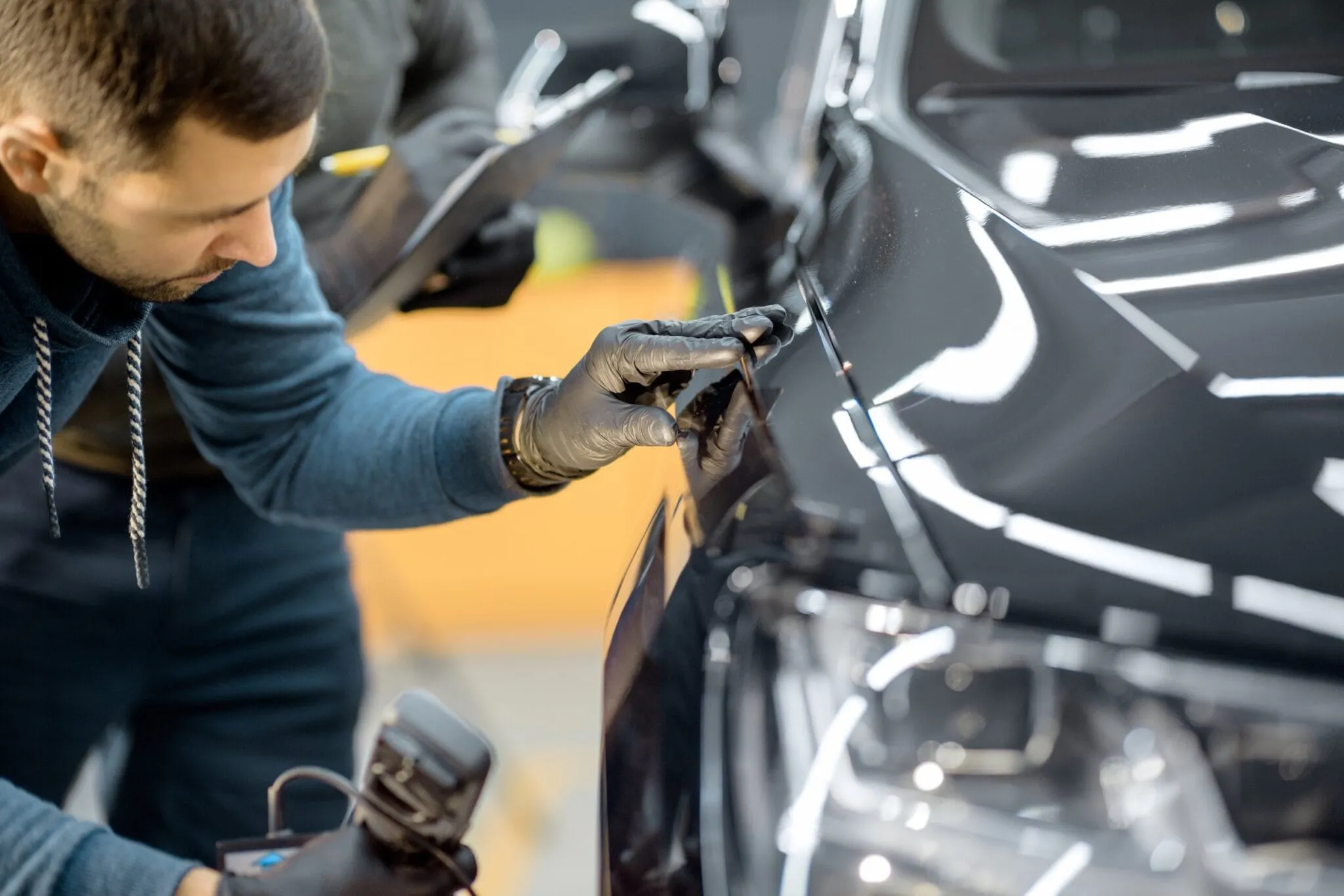 Technician inspecting the headlight area of a dark car