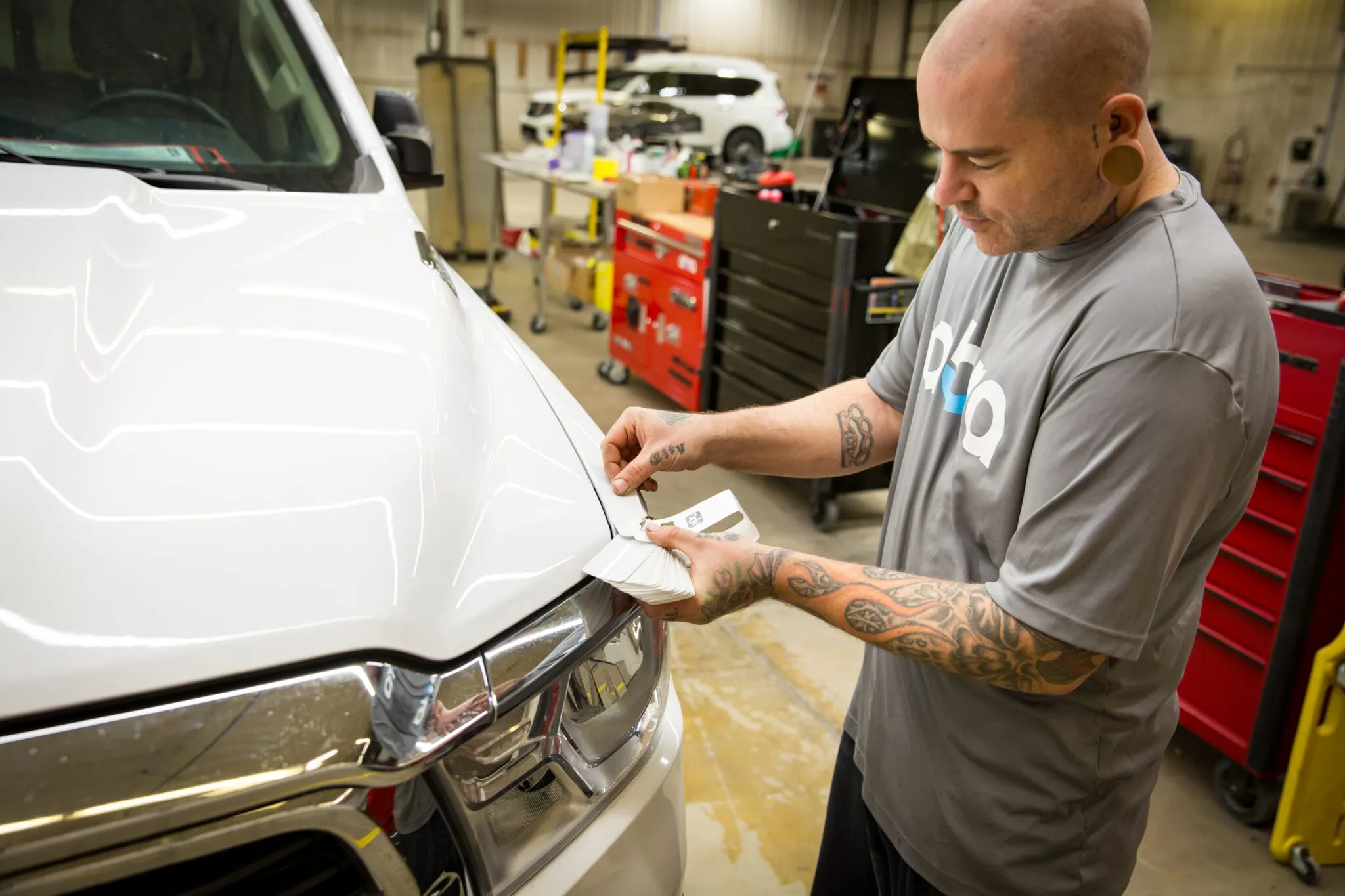 Technician checking paint on the hood of a white vehicle