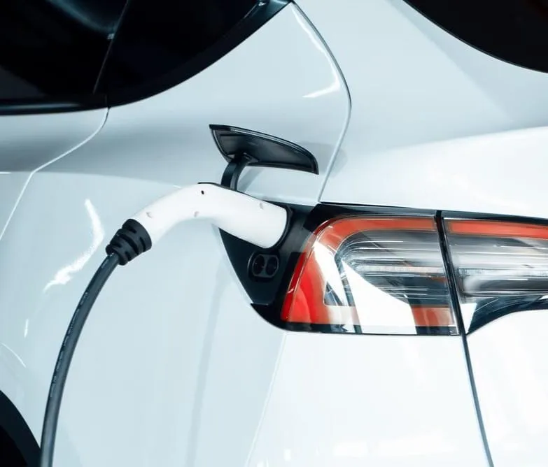 Charging cable plugged into the rear charging port of a white electric vehicle