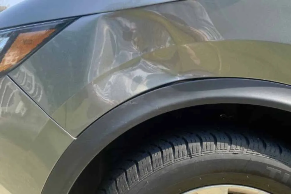Dent in the fender of a grey car