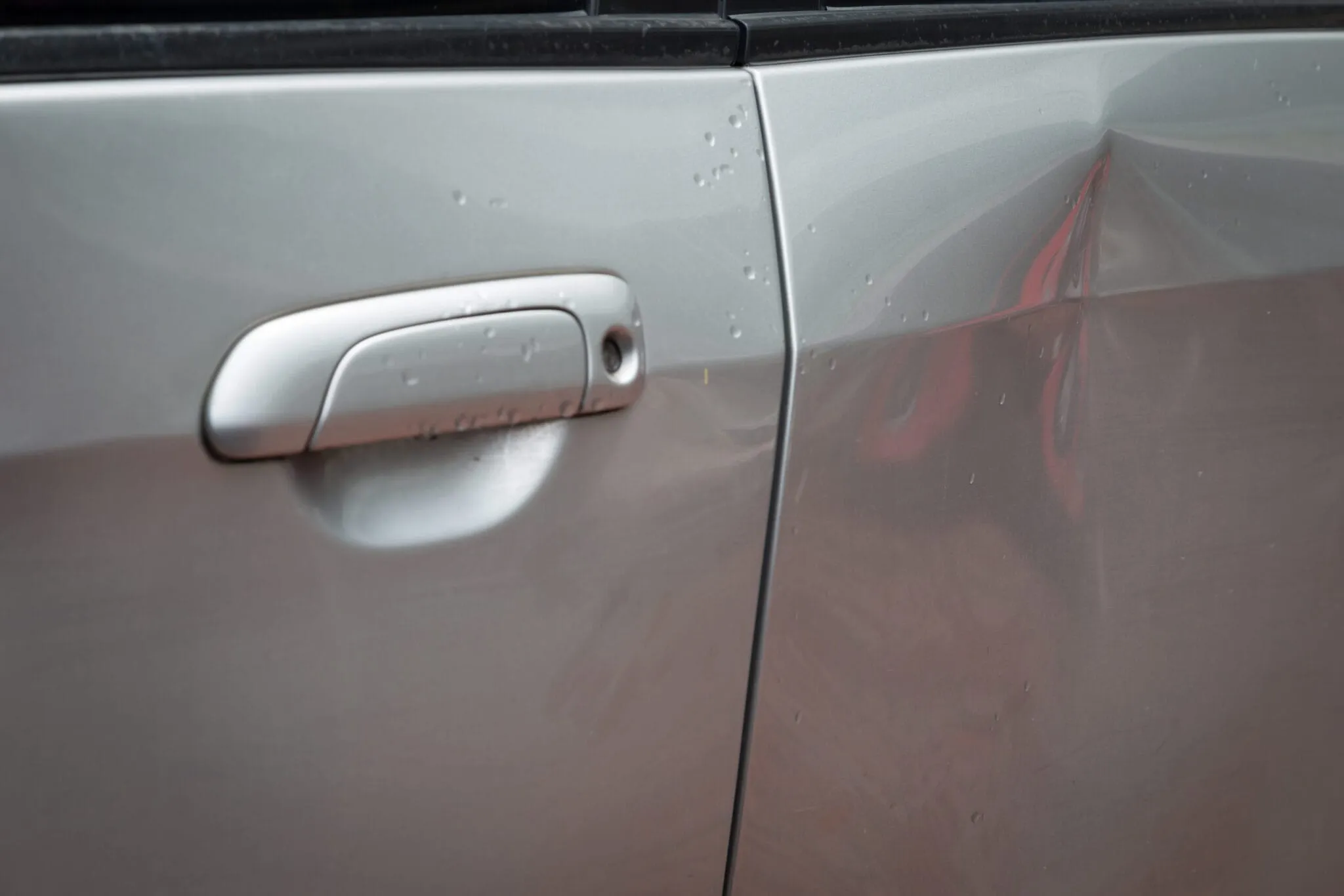 Crease in a silver car door panel