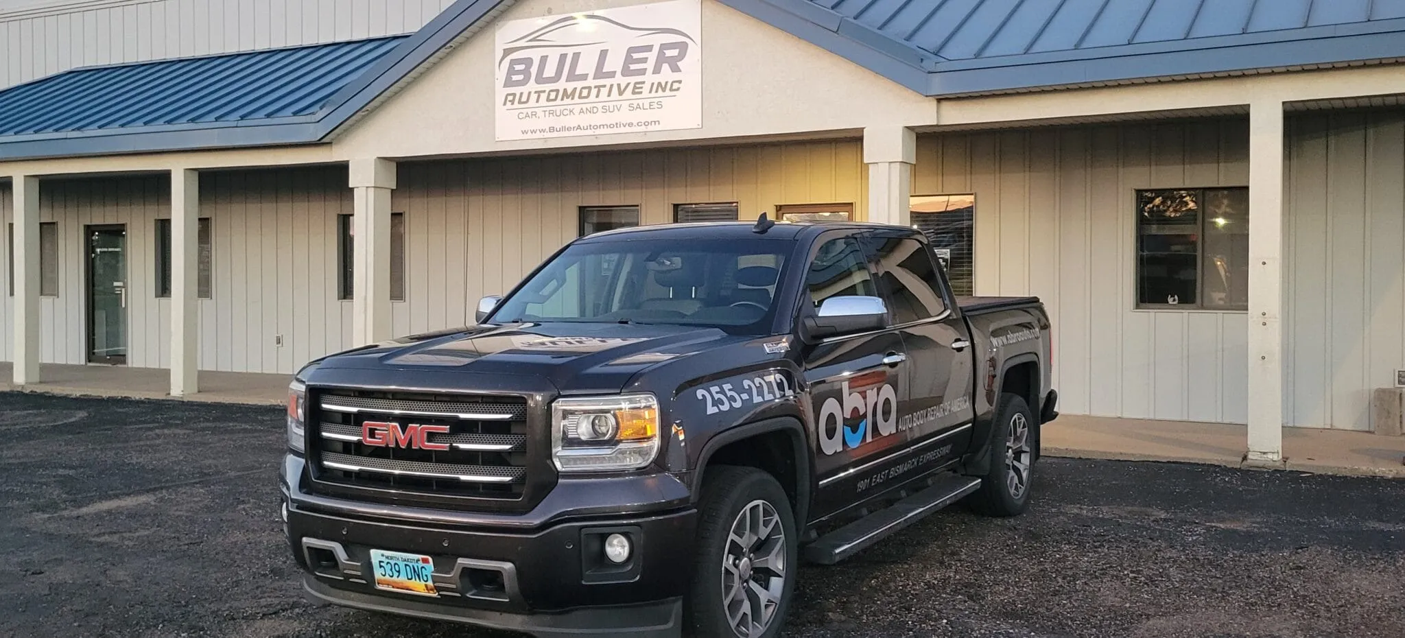 Dark pickup truck parked in front of a single-storey building