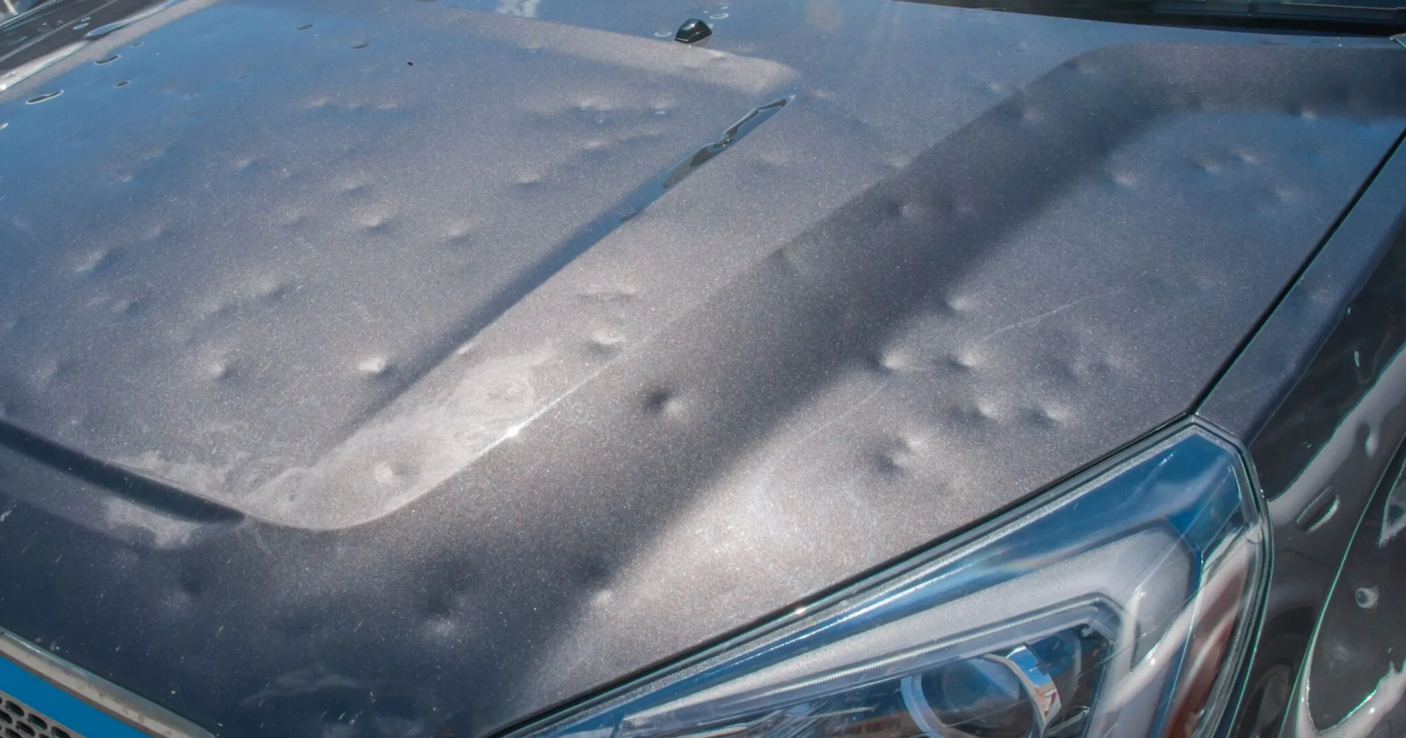 Hail dents across the hood of a car