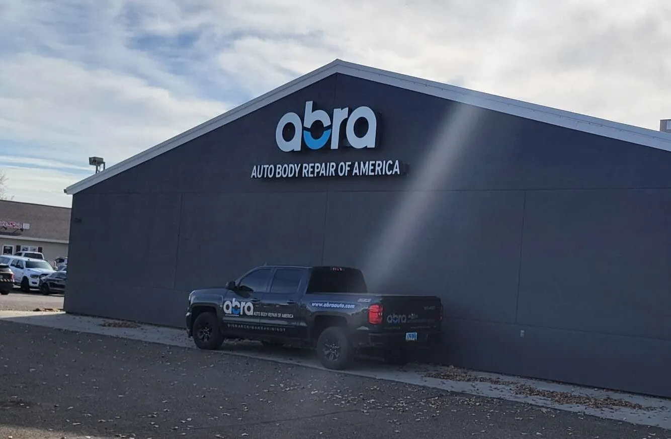 Dark grey shop building with the ABRA sign and a pickup parked in front