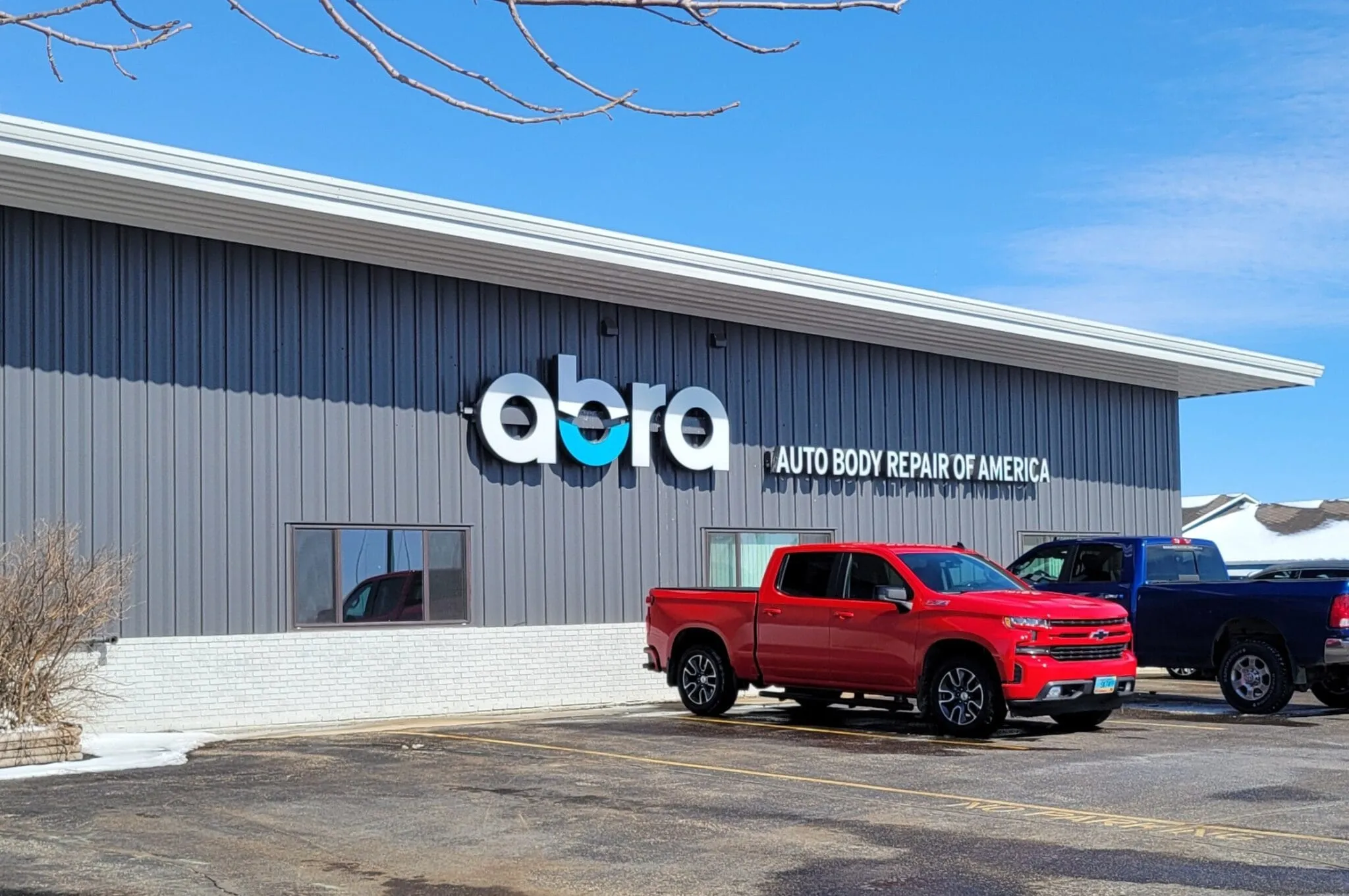 Shop building with the ABRA sign and a red pickup parked in front