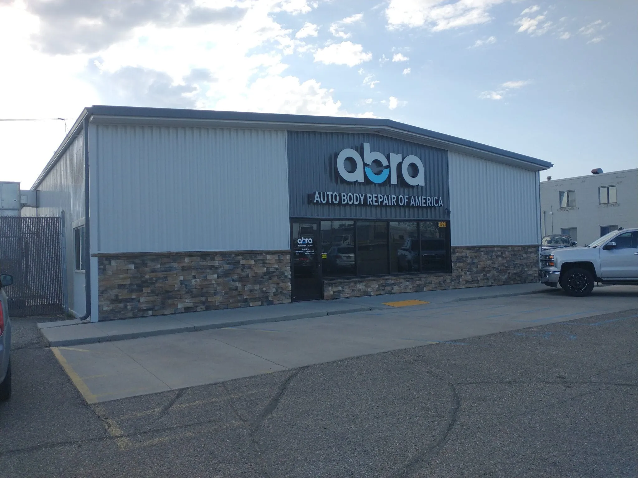 Shop building with a grey metal facade, a stone base and the ABRA sign