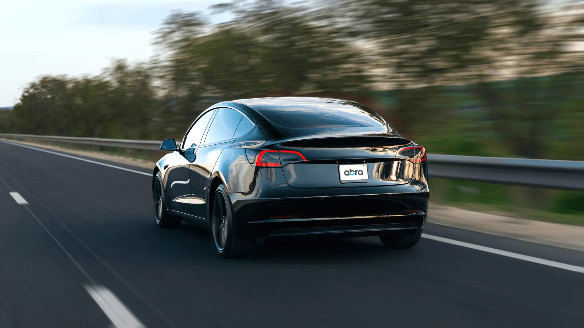 Black Tesla driving on a highway with motion blur